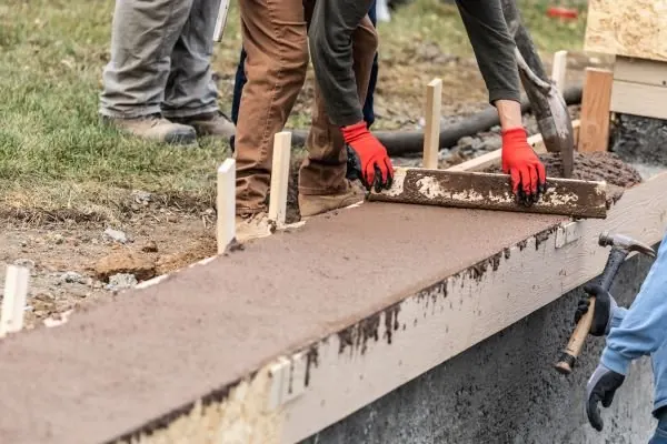 Concreter screeding a fresh concrete step against timber formwork