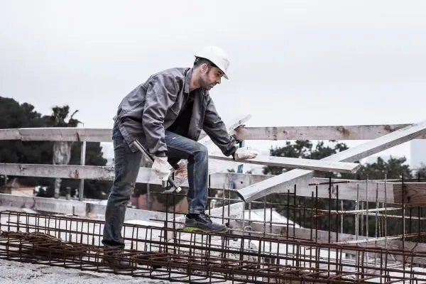 Worker in a hard hat tying steel reinforcement on a slab before the pour